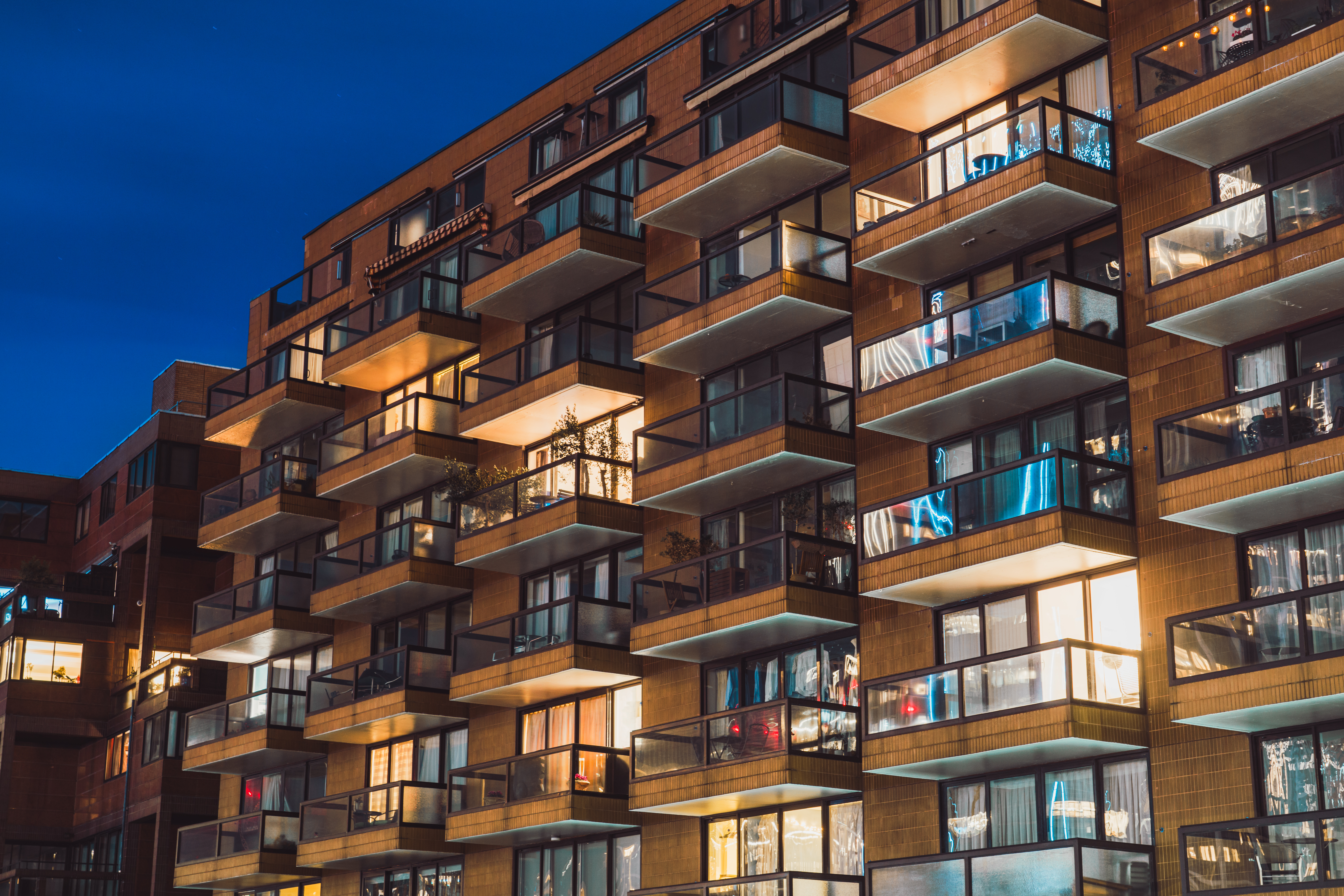 Warm lights shining from the windows and balconies of a contemporary apartment building in Pimlico, London, creating a cozy urban atmosphere at night